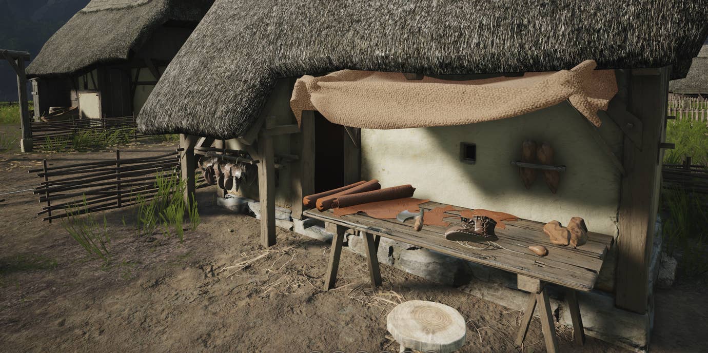 A wooden table under an awning by a house with some cloth and tools on it, from Manor Lords